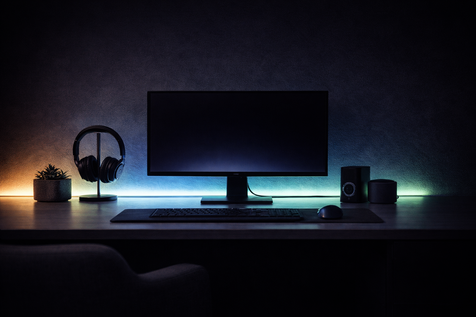 Dark office desk with computer monitor, keyboard, mouse, and speakers in a dimly lit room.